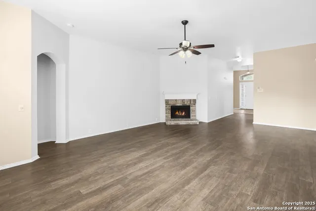 a view of a kitchen a ceiling fan wooden floor and a fireplace