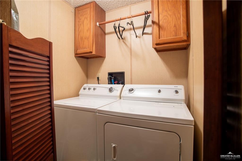 128 Nap Street Mission, TX 78572 - Photo 13 of 14 Dedicated utility area featuring a washer and dryer, wood cabinetry, and a clothing rod