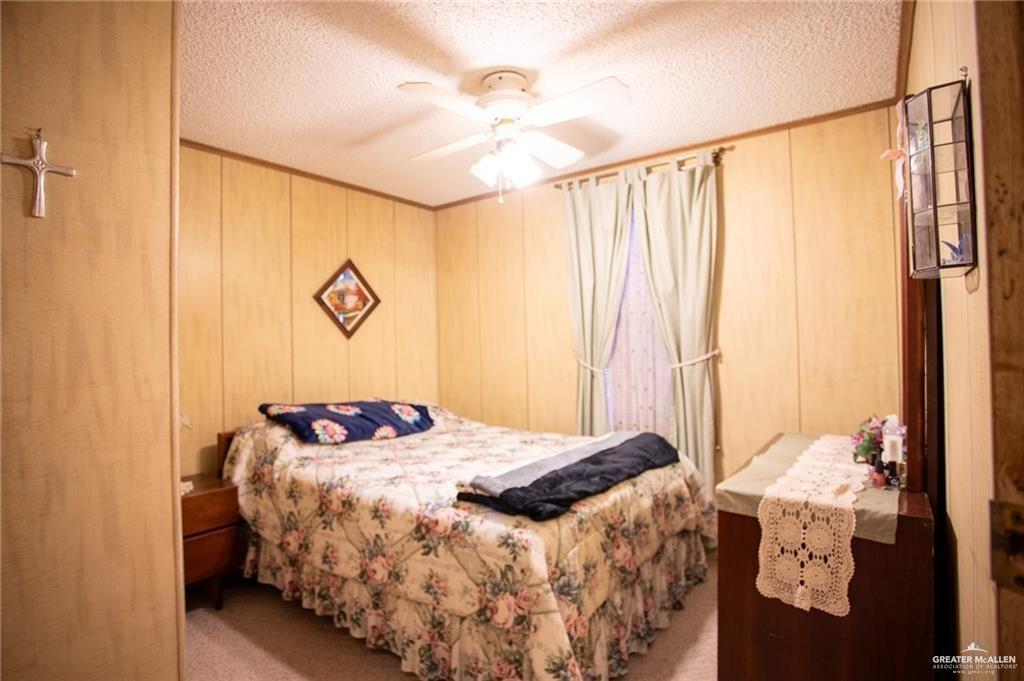 128 Nap Street Mission, TX 78572 - Photo 10 of 14 Bedroom featuring textured wood paneling, a ceiling fan with integrated lighting, and carpet flooring