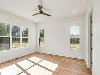 an empty room with wooden floor cabinet and windows