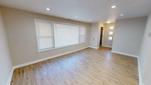 a view of an empty room with wooden floor and closet