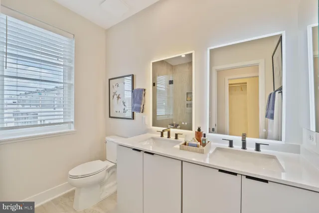 a bathroom with a granite countertop sink mirror and a toilet