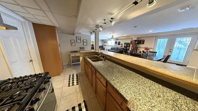 a view of a kitchen with kitchen island stainless steel appliances a sink stove and cabinets