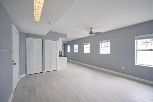a view of an empty room with a window and wooden floor