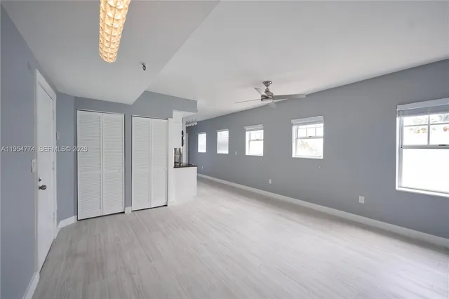 a view of an empty room with a window and wooden floor