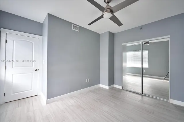 an empty room with wooden floor closet and windows