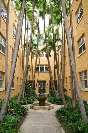 a front view of a multi story residential apartment building with yard and parking