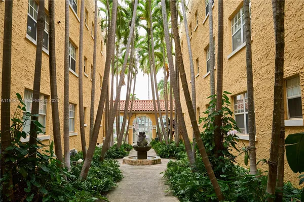a front view of a multi story residential apartment building with a yard and potted plants
