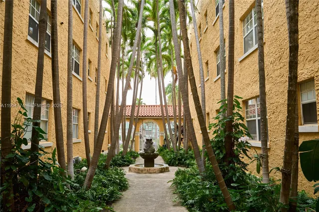 a front view of a multi story residential apartment building with a yard and potted plants