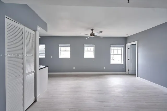 a view of an empty room with window and wooden floor