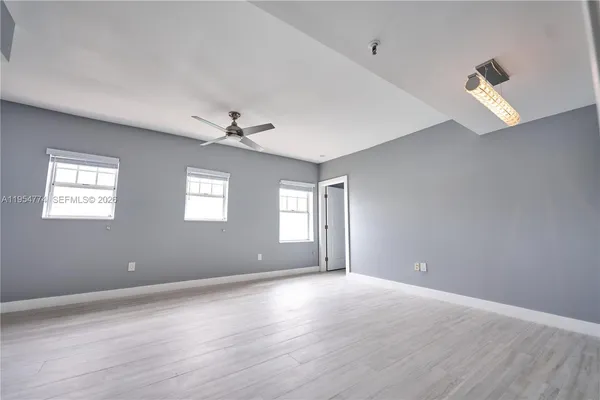 a view of an empty room with a window and wooden floor