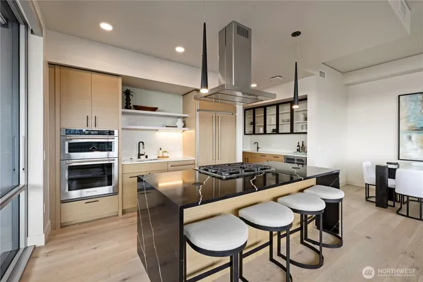 a kitchen with stainless steel appliances a stove a table and chairs in it