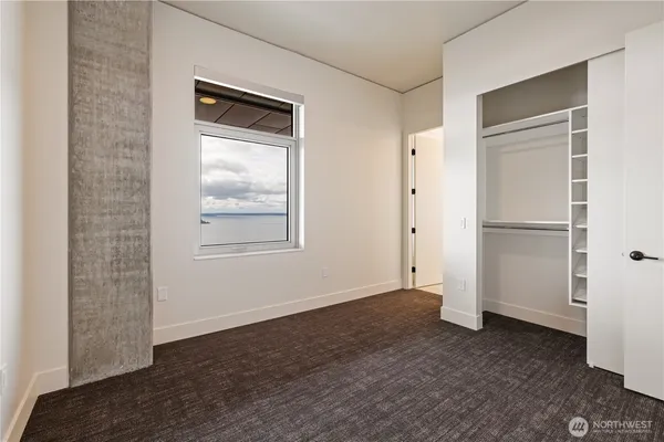 a view of an empty room with closet and windows