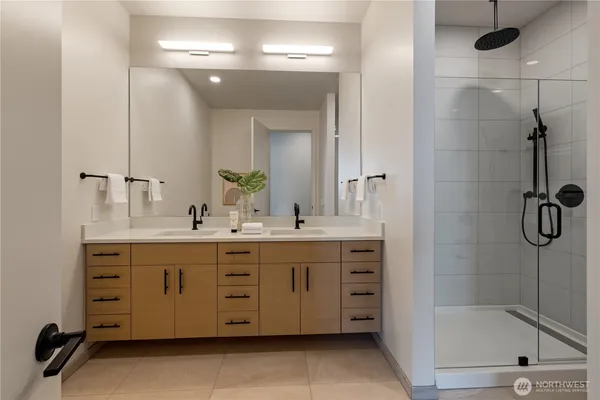 a bathroom with a double vanity sink a large mirror and shower