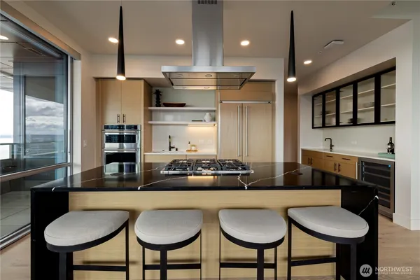 a kitchen with stainless steel appliances kitchen island granite countertop a kitchen island and chairs in it