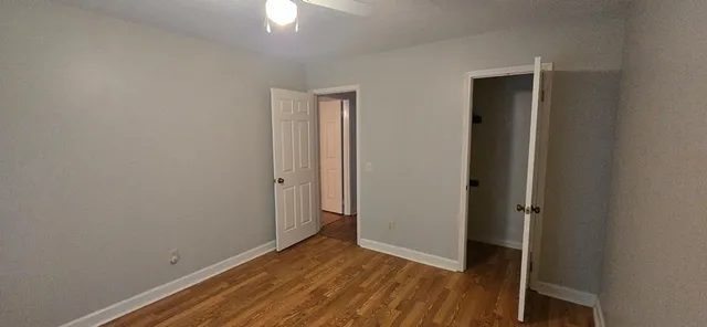an empty room with wooden floor closet and windows