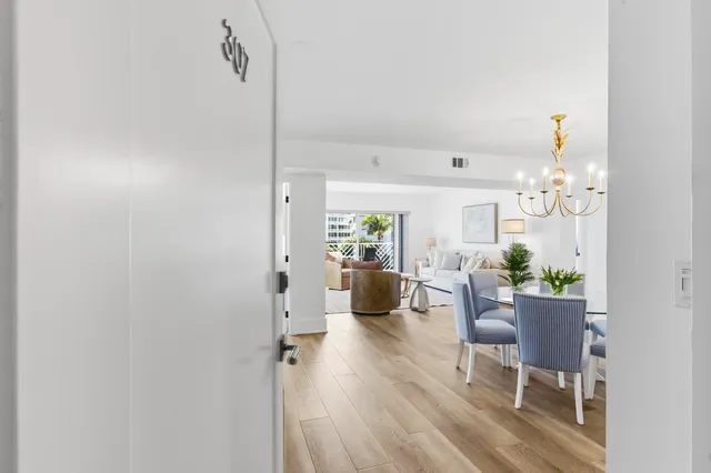 a dining room with wooden floor a chandelier a glass table and chairs