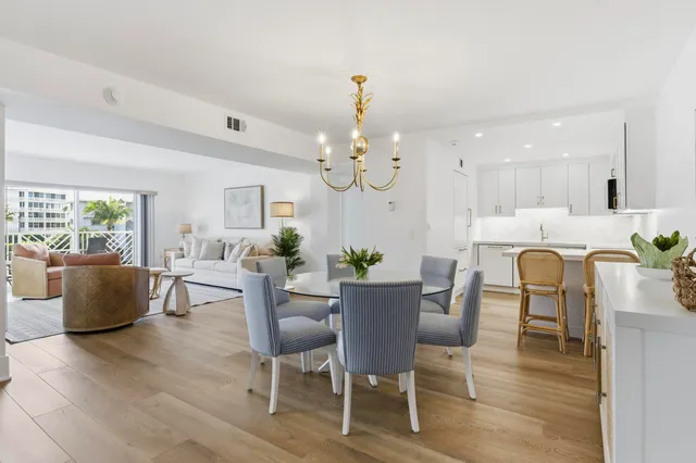 a dining room with wooden floor a chandelier a wooden table and chairs