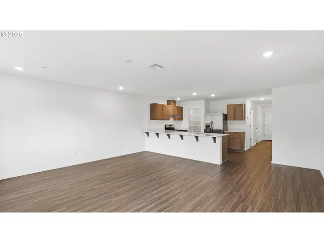 a living room with couches and kitchen view with wooden floor
