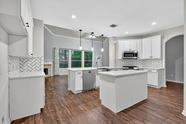 a kitchen with stainless steel appliances kitchen island wooden floors and white cabinets