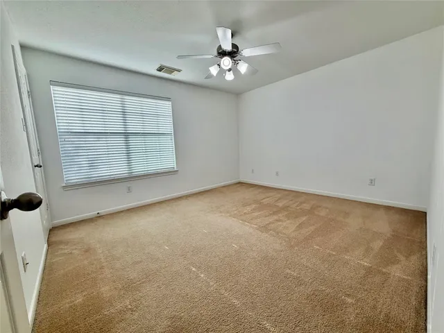 an empty room with a ceiling fan and window