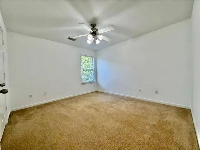 an empty room with a window and a ceiling fan
