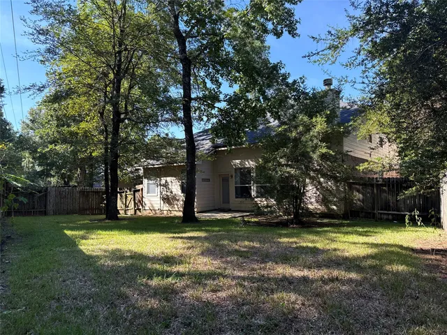 a view of a house with a yard and large trees