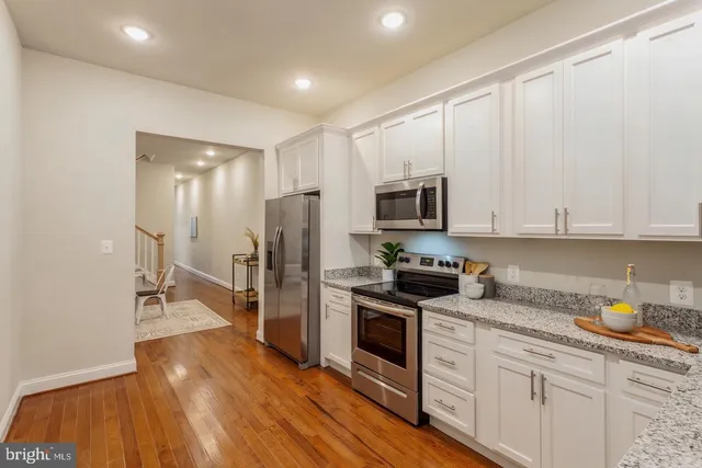 a kitchen with granite countertop white cabinets and stainless steel appliances