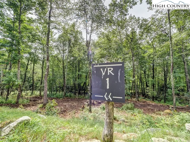 a sign that is sitting in front of a tree