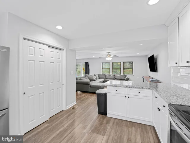 a kitchen with a sink dishwasher stove and white cabinets with wooden floor