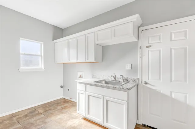 a kitchen with white cabinets and sink