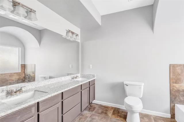 a bathroom with a granite countertop toilet sink and mirror