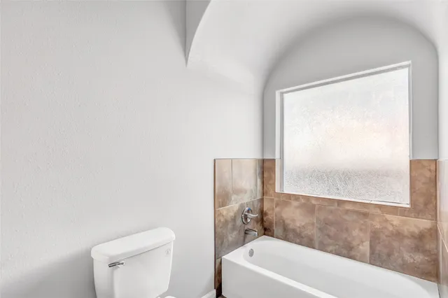 a white toilet sitting next to a bath tub