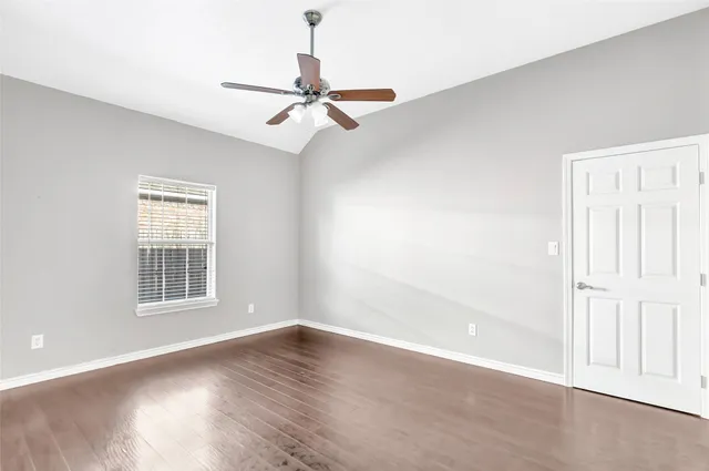 an empty room with wooden floor fan and windows