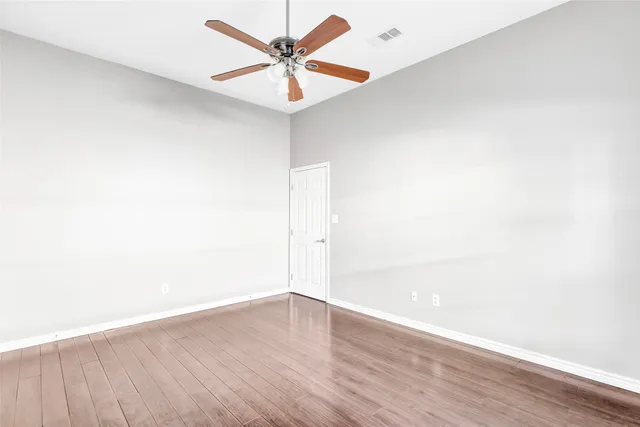 an empty room with wooden floor and fan