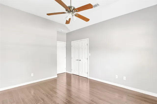 an empty room with wooden floor and fan