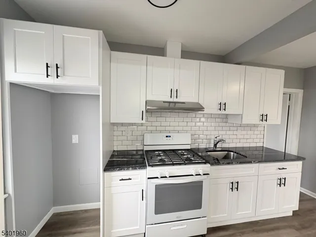 a kitchen with granite countertop white cabinets and white appliances