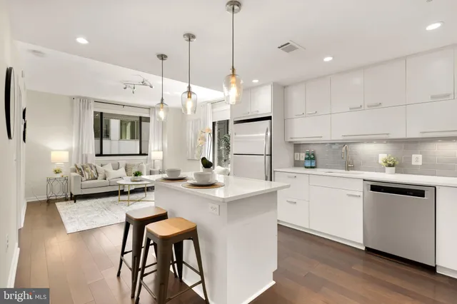 a kitchen with sink a stove and chairs with wooden floor