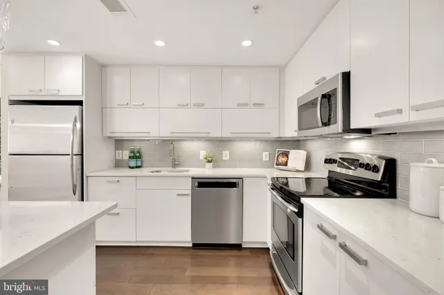 a kitchen with stainless steel appliances granite countertop grey cabinets a sink and a stove
