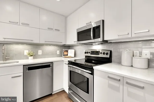 a kitchen with white cabinets and stainless steel appliances