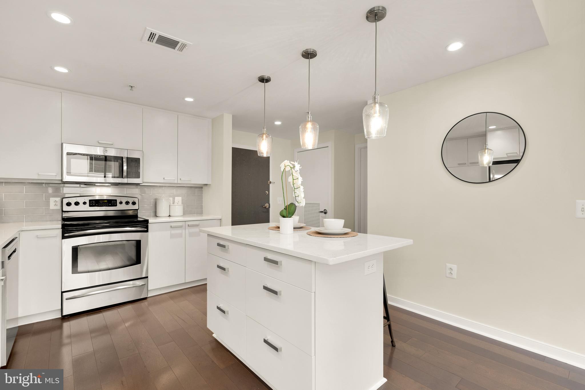 1010 Massachusetts Avenue Northwest, Unit 211 Washington, DC 20001 - Photo 7 of 27 a kitchen with kitchen island a sink stainless steel appliances and cabinets