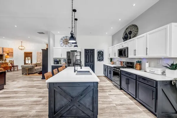 a large kitchen with lots of counter space a sink appliances and cabinets