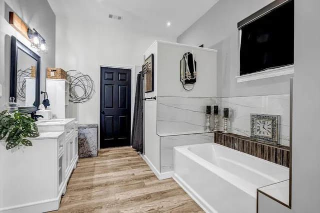 a bathroom with a tub sink and mirror
