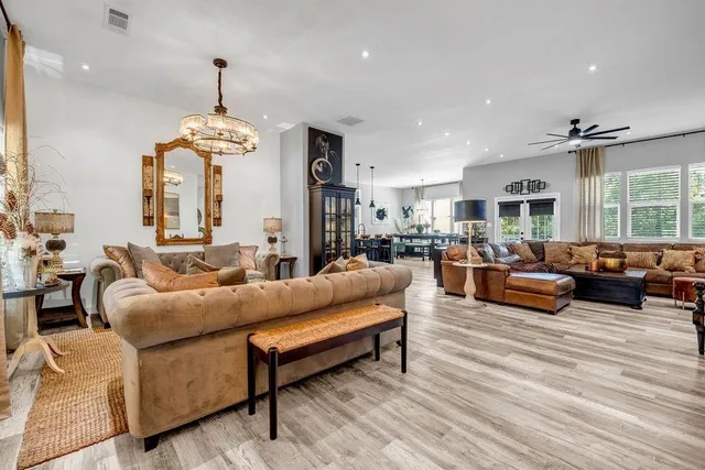 a living room with furniture kitchen view and a chandelier