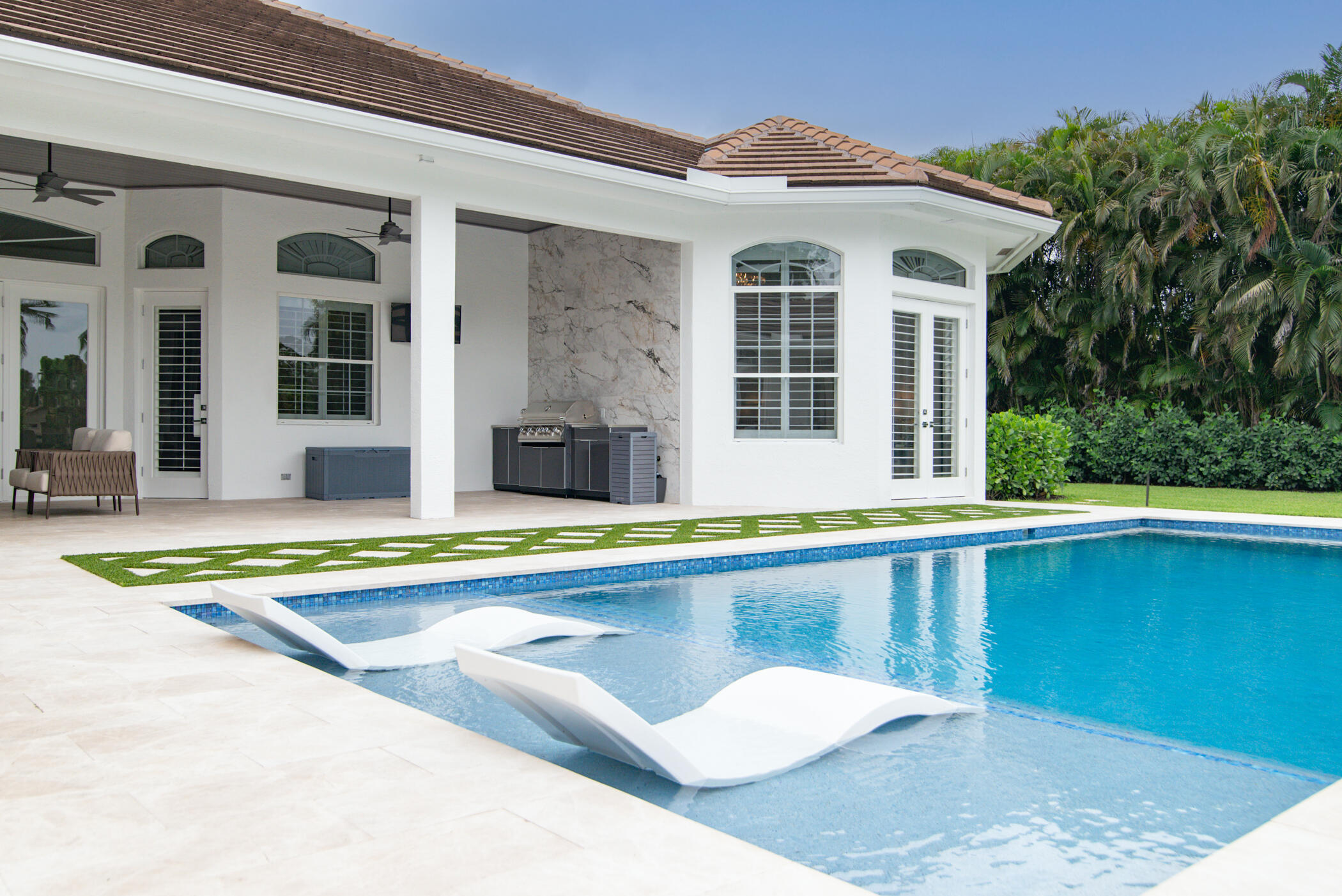 8246 Man O War Road Palm Beach Gardens, FL 33418 - Photo 10 of 55 a view of a white house with a large pool and a bench