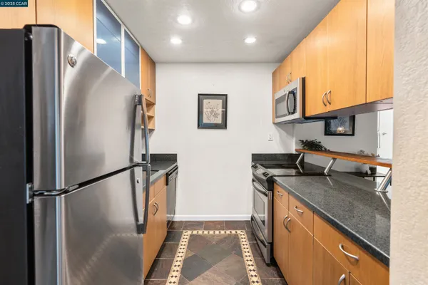 a kitchen with stainless steel appliances granite countertop a refrigerator a sink and a stove