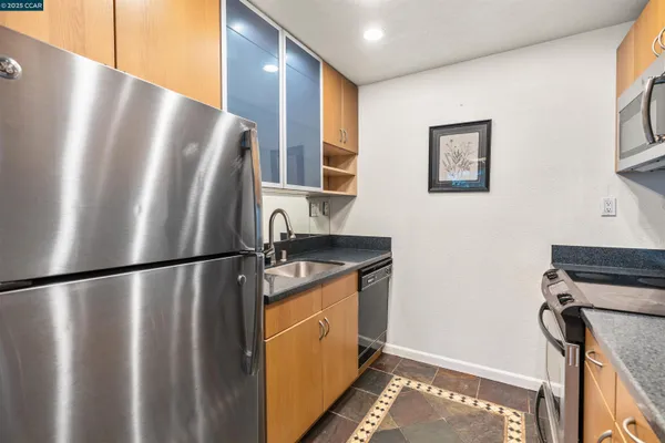 a view of a kitchen with stainless steel appliances granite countertop a refrigerator and a stove top oven