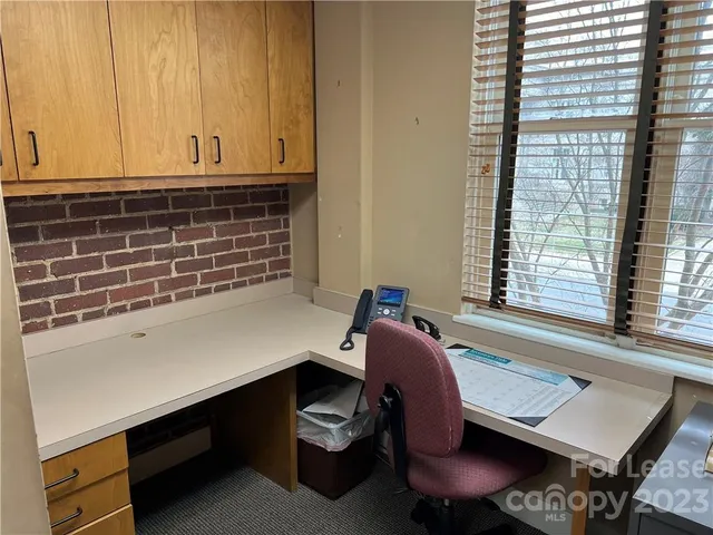 a view of a workspace with furniture and a window
