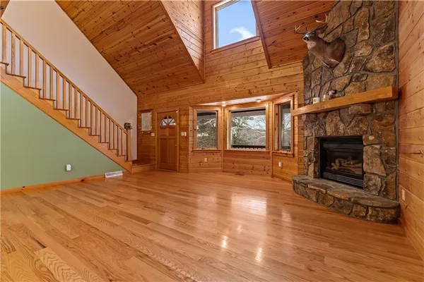a view of an empty room with wooden floor fireplace and a window