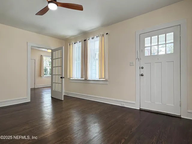 an empty room with wooden floor cabinet and windows